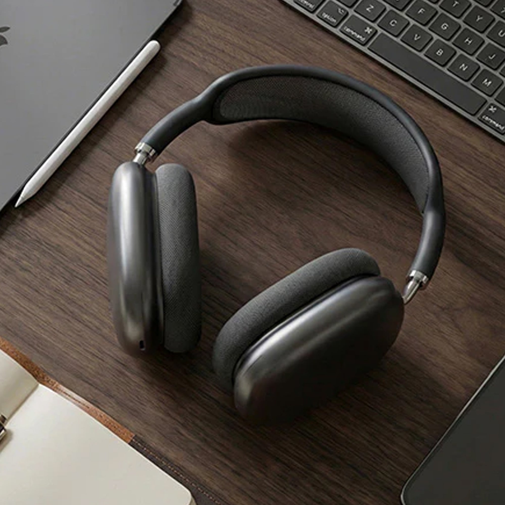 CTRL8 Bluetooth headphones with unique design placed on a wooden desk beside a laptop and notebook for work or study.