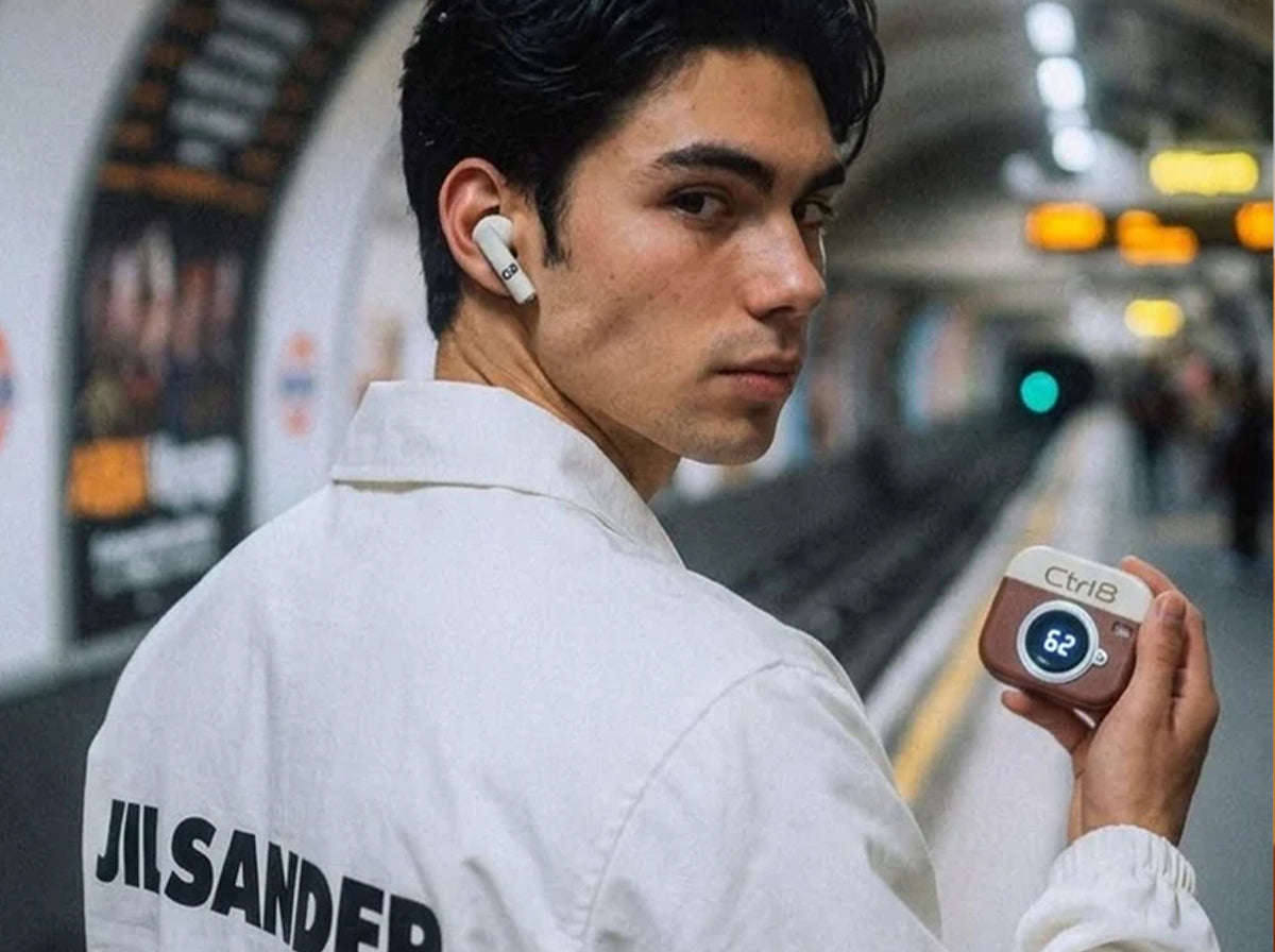 Commuter using CTRL8 Retro Camera Design Portable TWS Wireless Earbuds with stylish case and battery display at a subway station