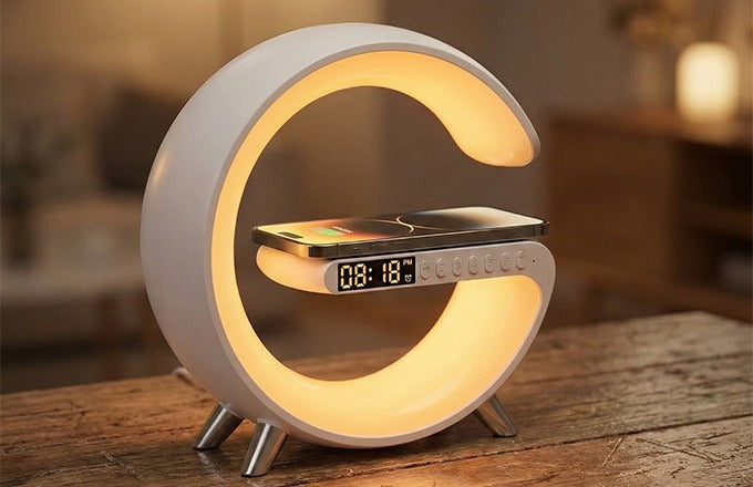 CTRL8 G-Shape Bluetooth Speaker with mobile charger and LED lamp on a wooden table in a warm, ambient room